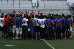 The entire football team in a huddle after the spring festival. The festival included a band, cheer, and Blue Belle performance.
