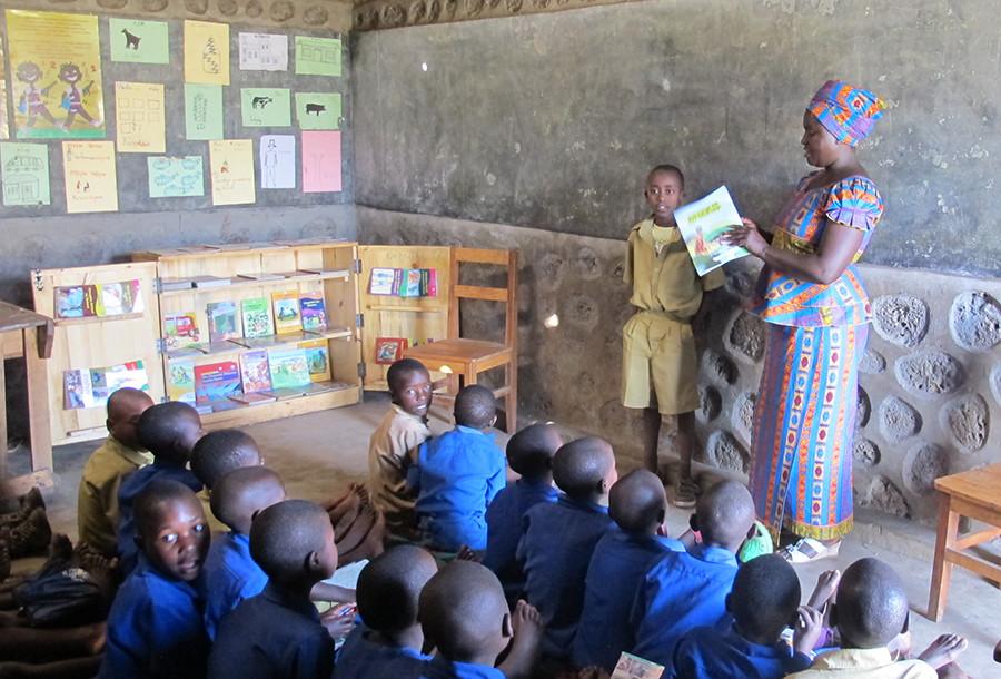 In Rwanda, Africa a 4th grade teacher reads a book to her class. Rwanda has a poor literacy rate teachers are trying to fix because the language spoken, Kinyarwanda, is only spoken in the small country of Rwanda so there are few books in the language.