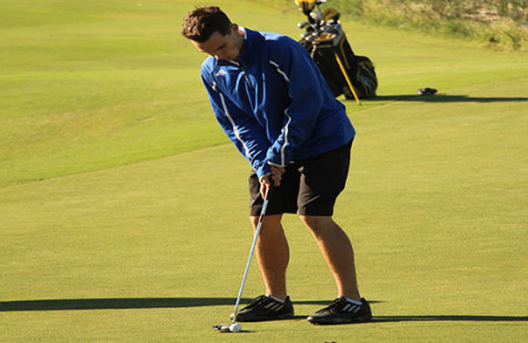 A boys golf member putting a golf ball. They would place fifth at Cottonwood Creek