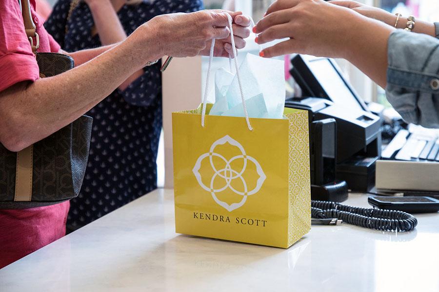 Kendra Scott bag displaying their logo. At all times, 20% of their proceeds from their charms go to a local or national beneficiary.