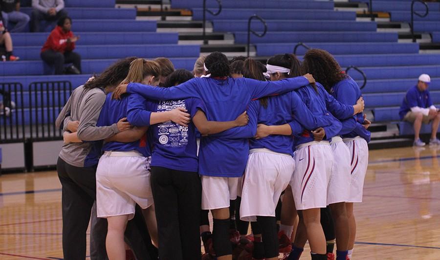 The varsity girls huddle together before a game. Some of the girls have played together since middle school.