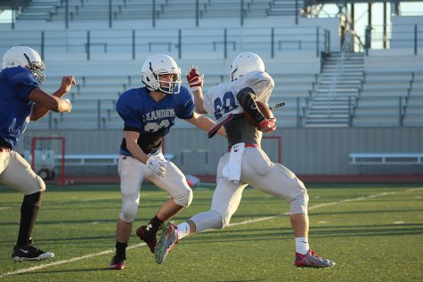 A running back prepares to attempt a stiff arm on a defender. At this point they were practicing their running offense against the defense.