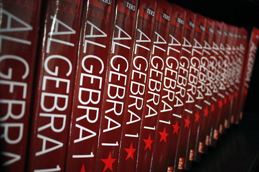 A row of algebra one textbooks. After taking this class as a high school freshman, it is retaken as a college freshman.