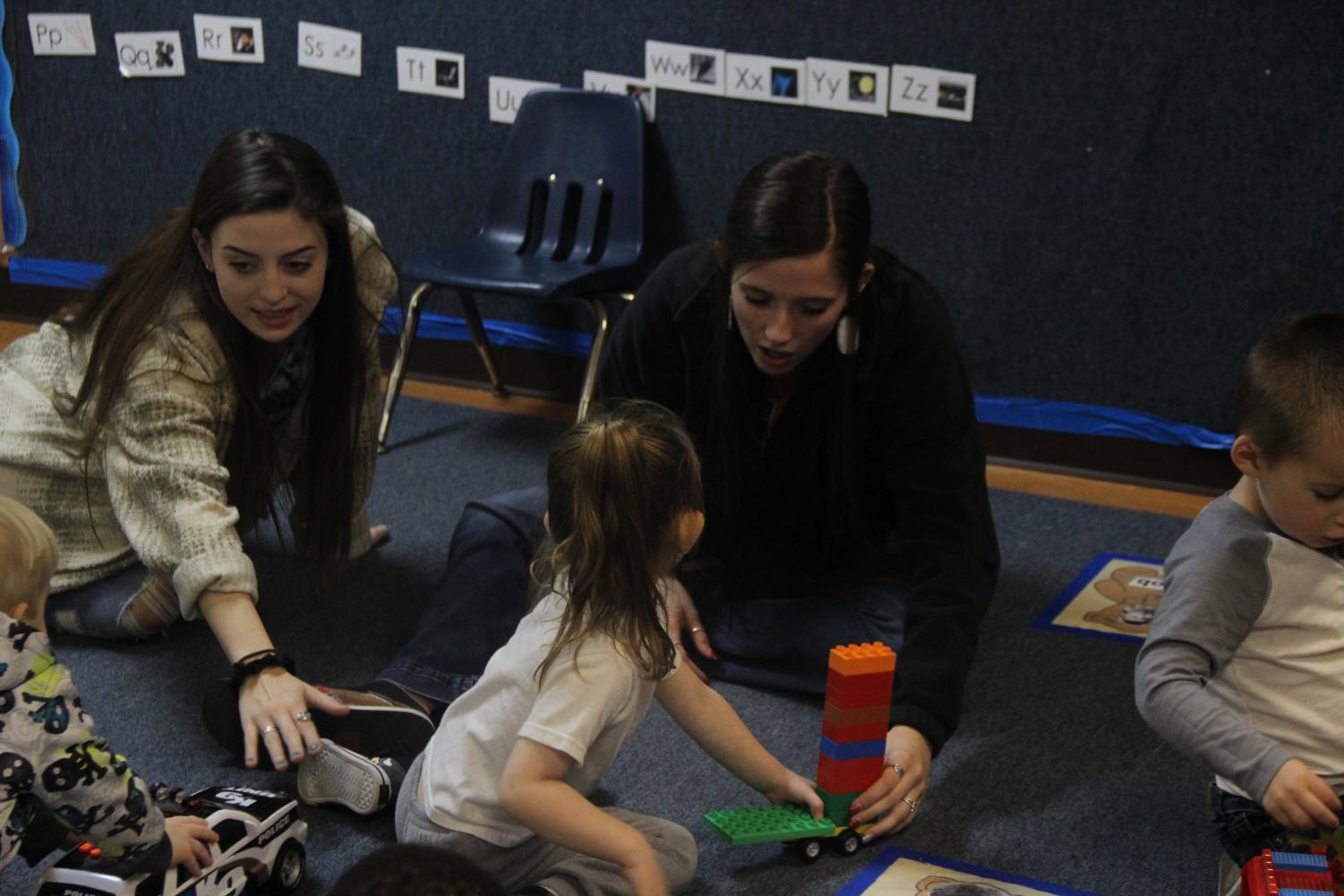 Juniors Madison Stathos and Abbey Saunders spending time with kids who attend Head Start. This is their first year in the program.