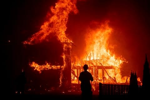 A fireman stands in front of a burning building.