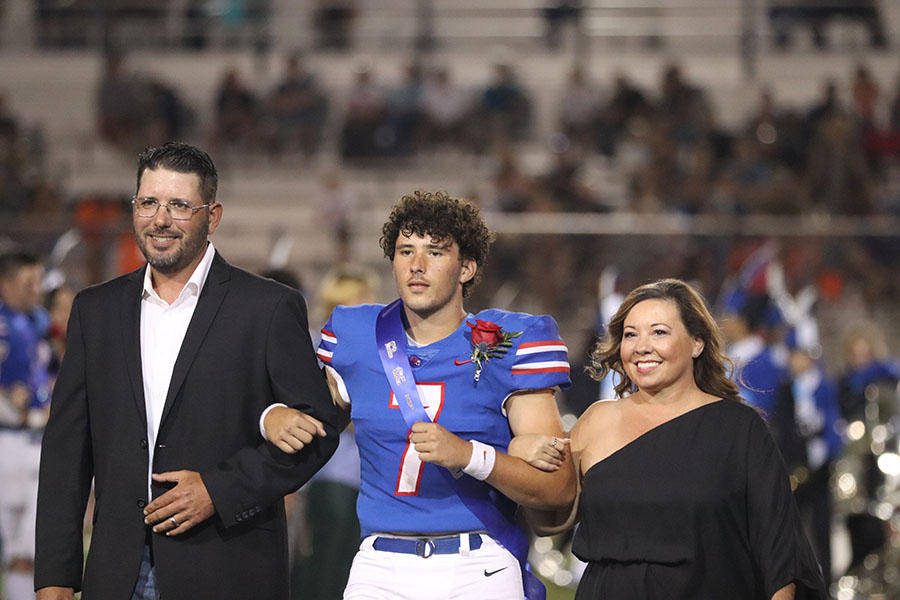 Senior prince Cameron Burkman walking down the field with his parents after being announced senior Prince.