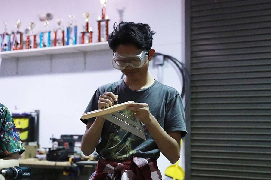 Junior Paul Hui measureing a peice of wood for the feild 
