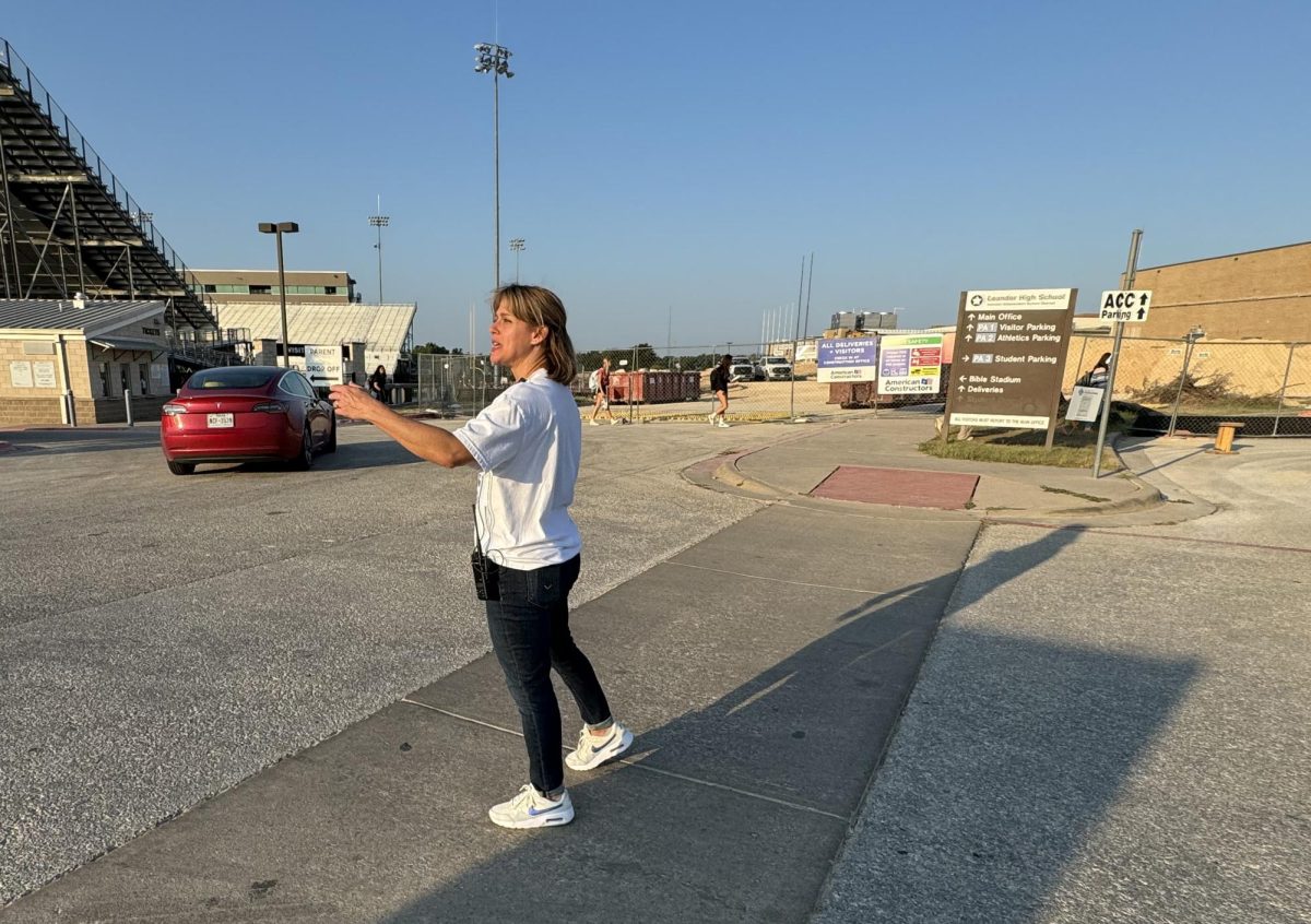 Mandy Moore, assistant principal, directs traffic on the second day of school. The new traffic pattern due to construction was challenging for faculty, staff and students. Students all had assigned parking spots some in front of the school and some in back.