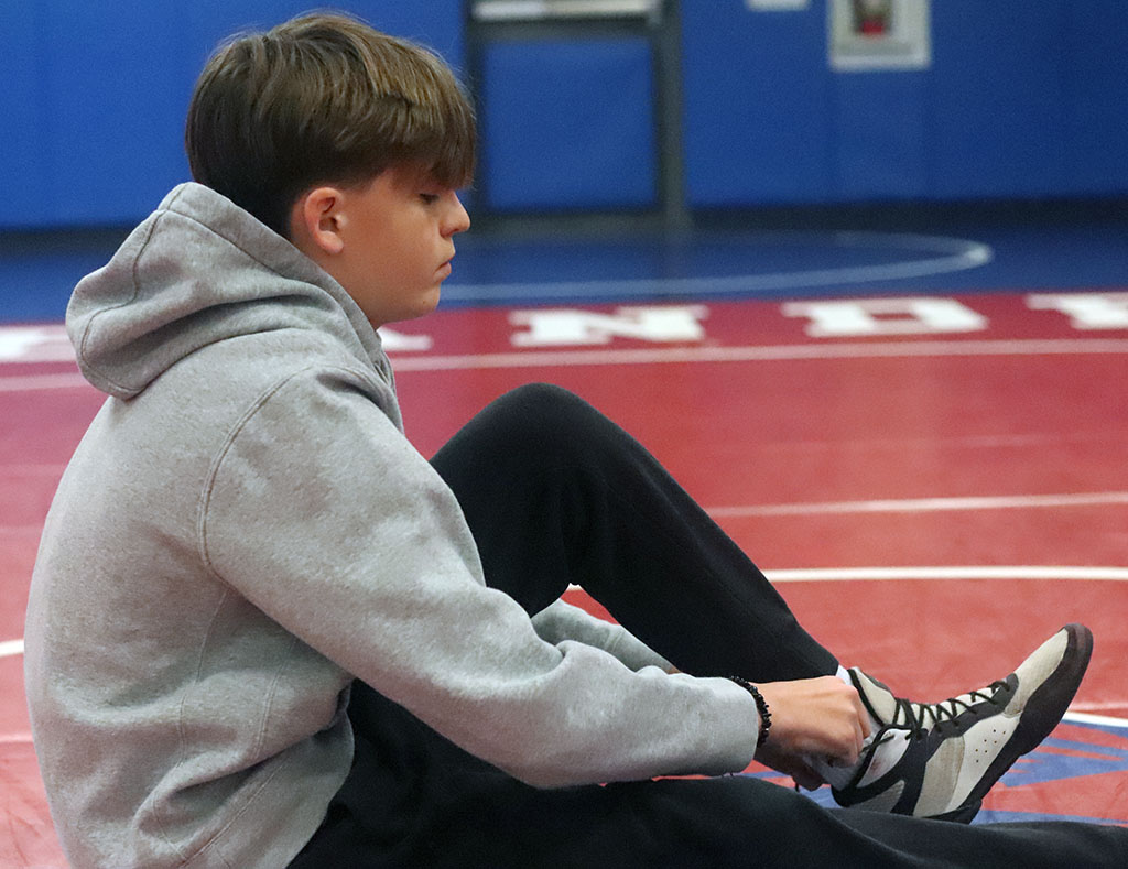 Sophomore Jacob Irvine laces up his wrestling shoes in preparation for practice in the wrestling room. Wrestling from a young age, Irvine harbors fond feelings towards this gym. “That’s where we get to practice and where we don’t have to pretend to be anything we’re not,” said Irnvine. “Practices are hard… once you’re done, you feel [accomplished]."