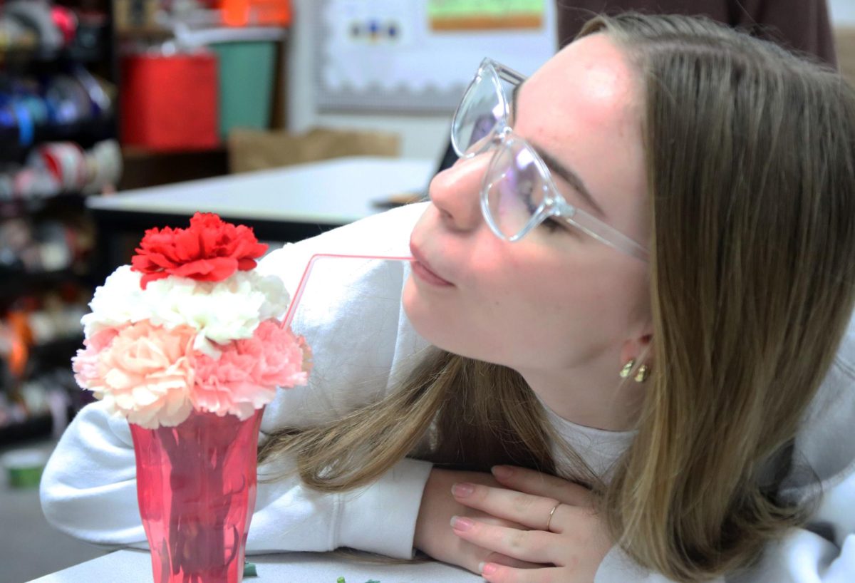 Posing with her milkshake-themed floral arrangement, sophomore Reece Hamilton pretends to sip from the striped straw. Based on a couple's ice cream sundae, the design aimed to bring cheer to students leading up to Valentine's Day. "It was actually pretty easy and fun," Hamilton said. "I already had my pattern lined out in my head, so I didn't have to think of where all the flowers would go. The hardest part was cutting them to size.”
