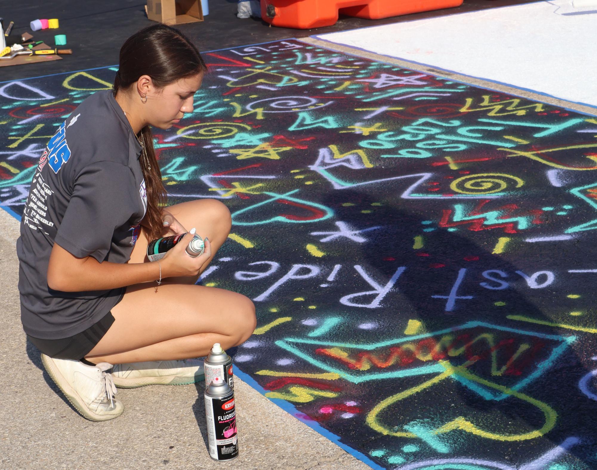 Maddlyn Lee paints her senior parking spot Aug. 9. Lee said, "I saw this idea, and thought using spray paint would be easier but still bright and fun.  I wanted to participate so I could document my senior year and have lots of photos."