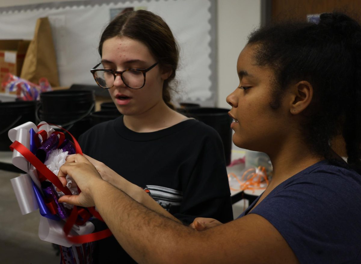Hope Stevens fixes her ribbons on the base of her mum in floral design for homecoming week.