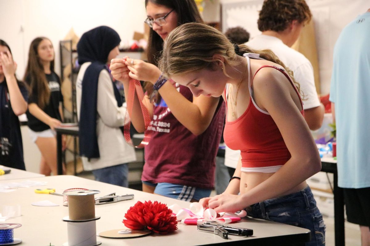 Hope Stevens fixes her ribbons on the base of her mum in floral design for homecoming week.