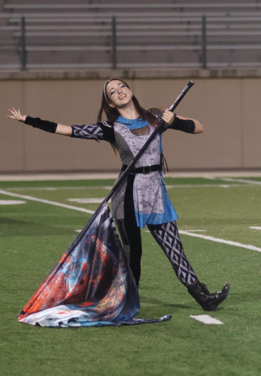 Part one of "curiouser and curiouser" comes to an end during the festival of bands on sept.29 at Gupton Stadium. Senior Jenessa Nagel finishes the part by posing with her flag.