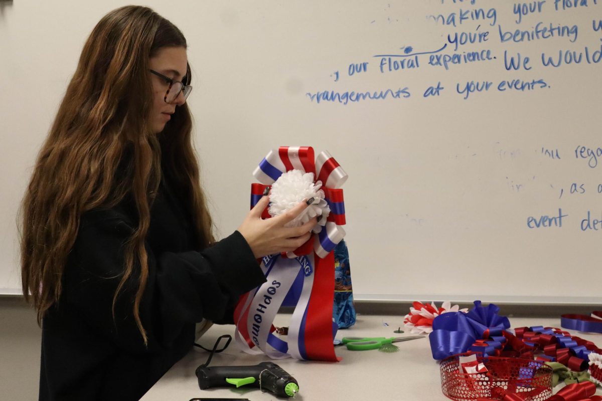 Junior Violet Dunnam glues her reasonably-sized mum together in the school colors red, white and blue.