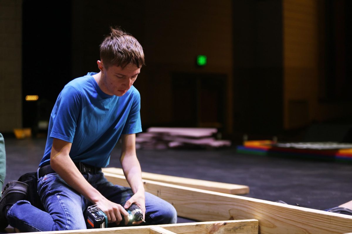 Junior and assistant sound designer Cory Wyatt screws together the bones of a set piece for the musical production "Singing in the Rain."
