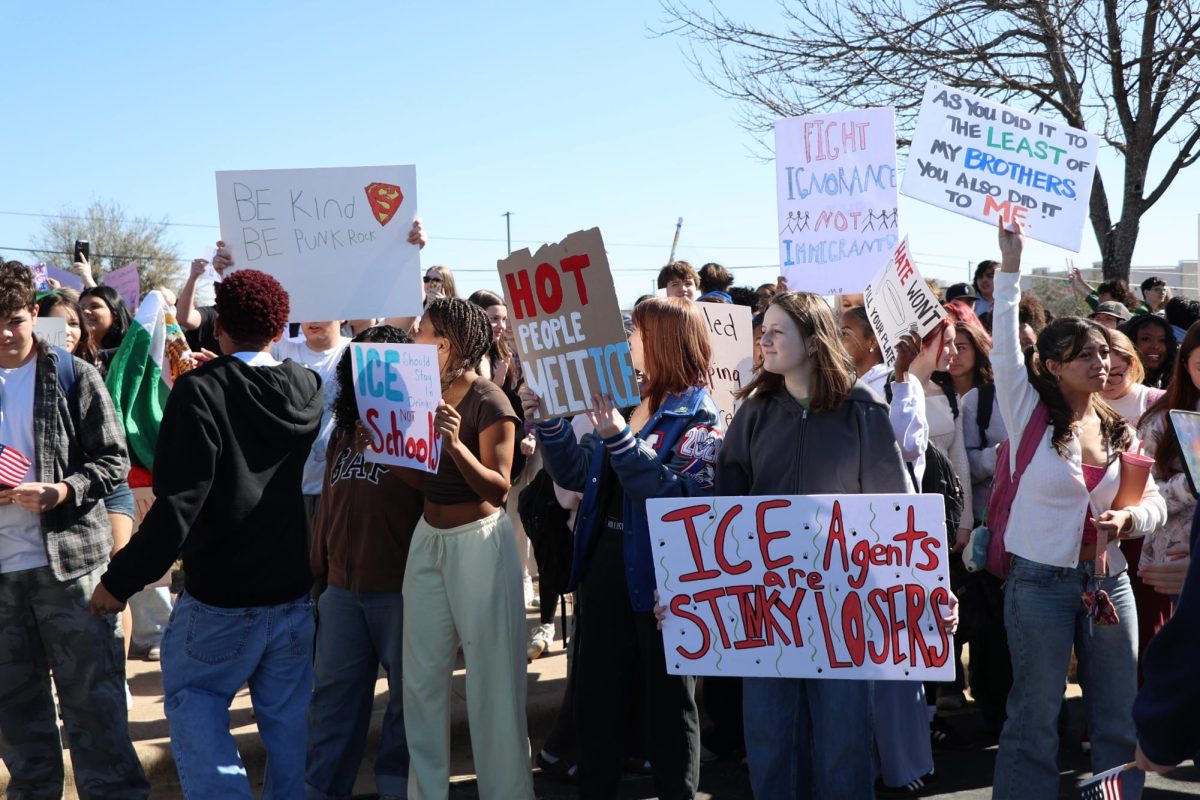 Students yell and hold aloft signs protesting ICE. Posters referenced pop culture moments, historical quotes and colloquial slang.