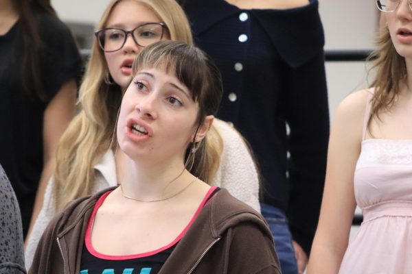 Junior Chloe Orovio sings during warm ups. With mere days until the choir's appearance at the competition, Director Christian Clow paid special attention to the sopranos' vowel sounds.  
