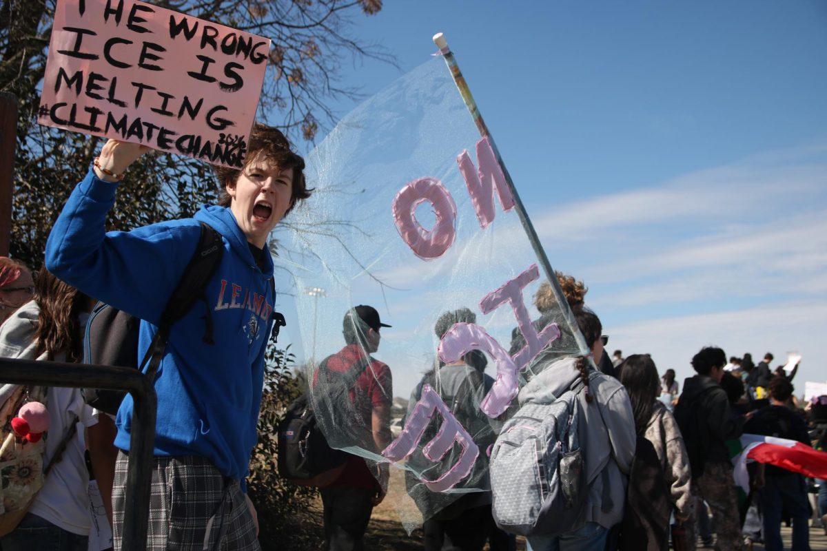 Sophomore Noah Hill raises his sign while marching at a student walkout protest on Feb. 4 in front of Leander High School.