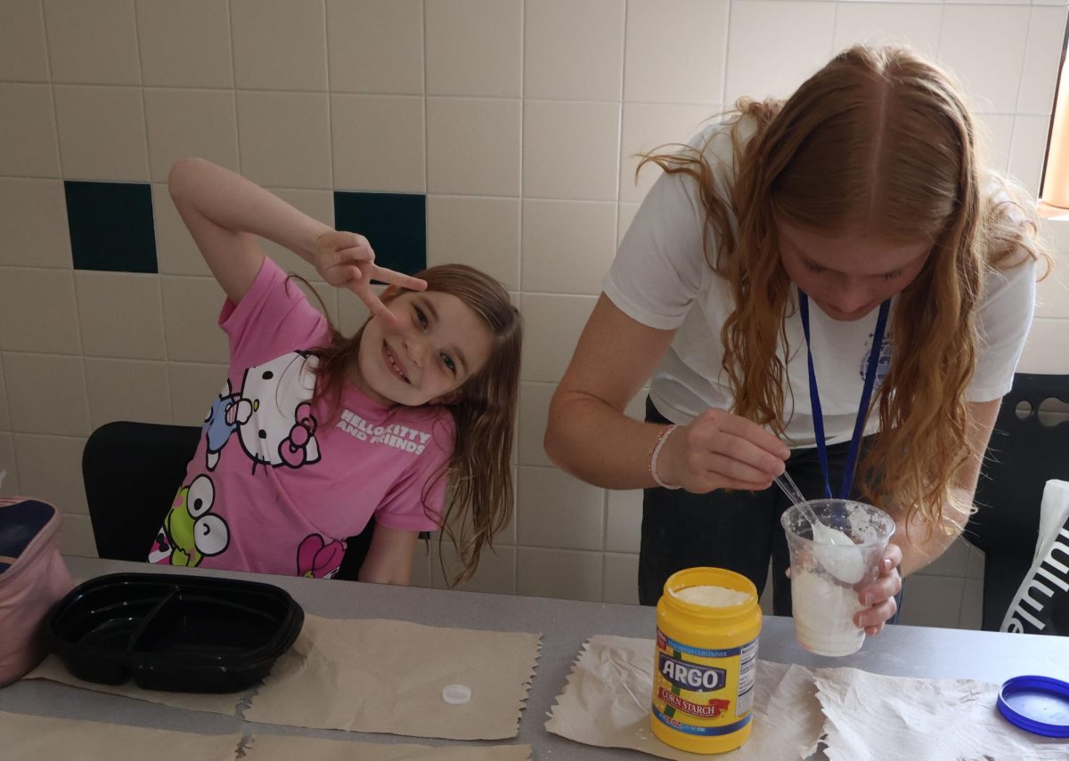 Senior Emma Tolman measures the amount of cornstarch to use for the ooblek on March 30 while her PALee strikes a pose.