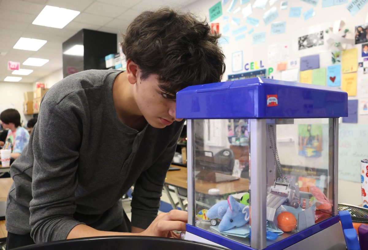 Sophomore Jameson Dowling tries his luck on on-level Chemistry teacher Kelly Stephens's miniature claw machine that provides students an opportunity to win prizes ranging from candy to fake currency on April 22 in Room 2004 during seventh period. 