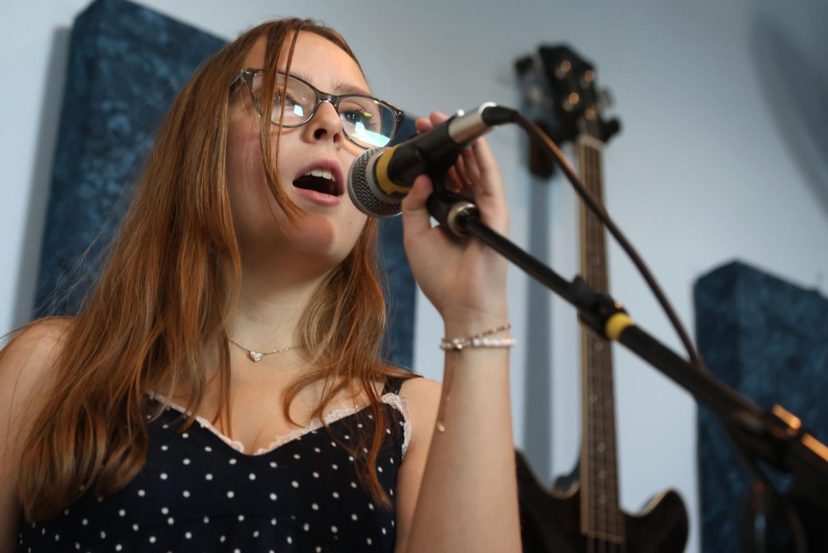 During band rehearsal in preperation to preform at the IB banquet, junior Violet Brewer sings to the song "Babydoll" by Dominic Fike at Randa School of Music May 9. "My favorite thing about the band is that I have gotten to know a few new people. We have become really close as a band and gotten to know each other." Photo by Marilyn Rutschman