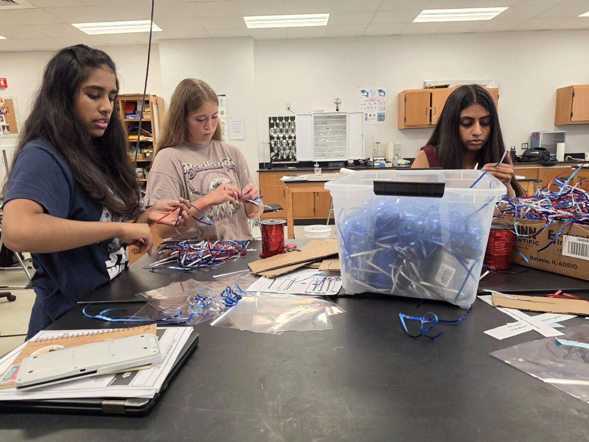 Juniors Geetika Joshi, Scarlett Geurin and Mahi Patel organize different colored streamers in preparation for "Kiss" a Senior Goodbye, taken May 27.