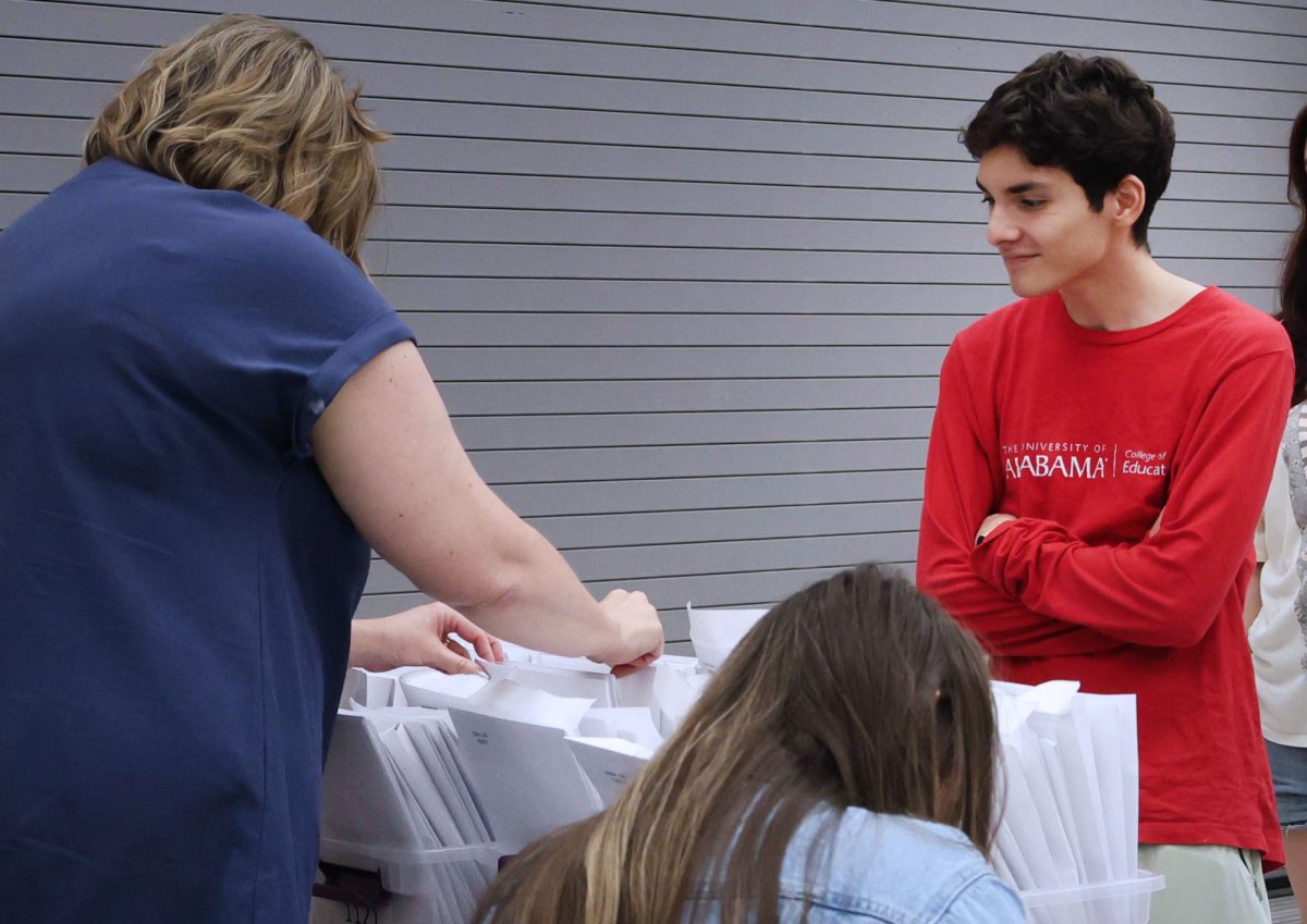 Jordan Ibarra picks up his chords and awards from a table in the cafeteria before graduation practice.