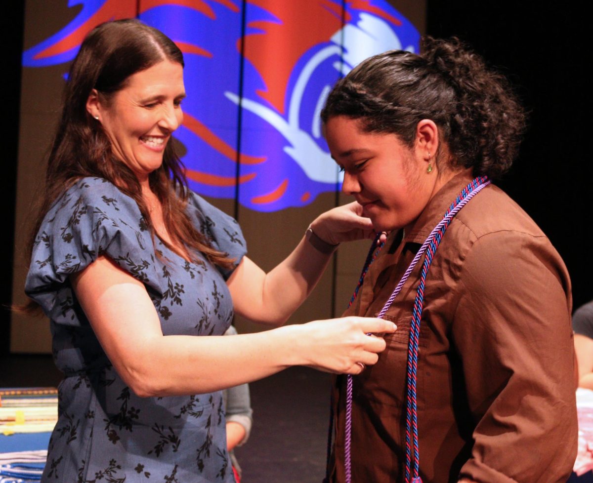 Dual credit coordinator Megan Wolske gives Senior Gabriela Benitez dual credit cord at senior awards ceremony in the performing arts center May 20.