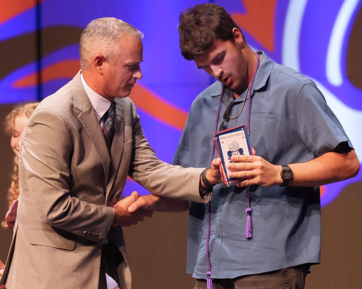 After winning the male Lionheart award, senior William Wells tries to put his award back together with the help of Principal Chris Simpson  May 20.